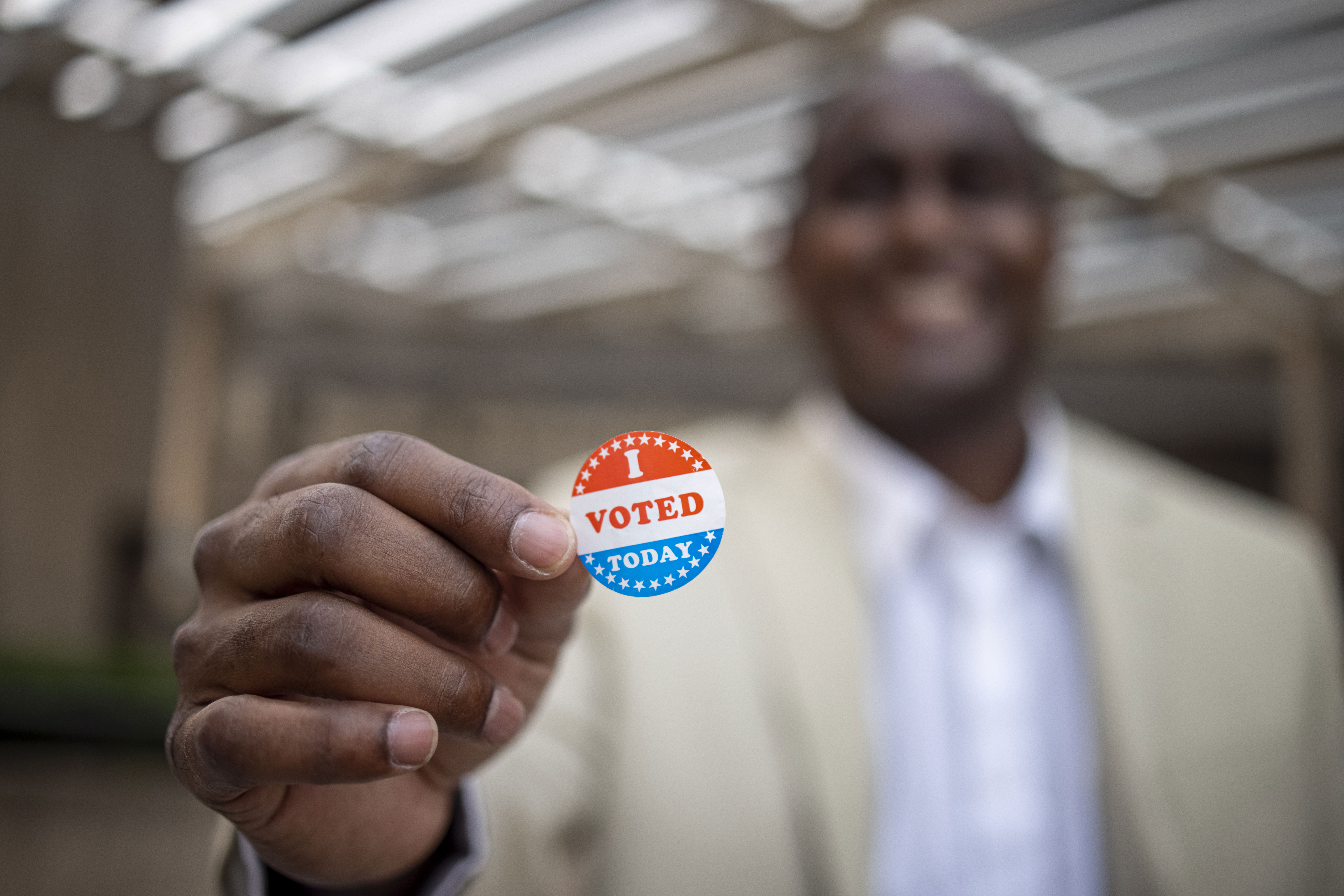 Man with tan jacket holding "I voted today" sticker