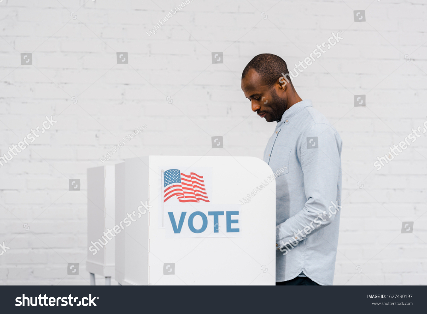 Photo of a black man voting in a booth.
