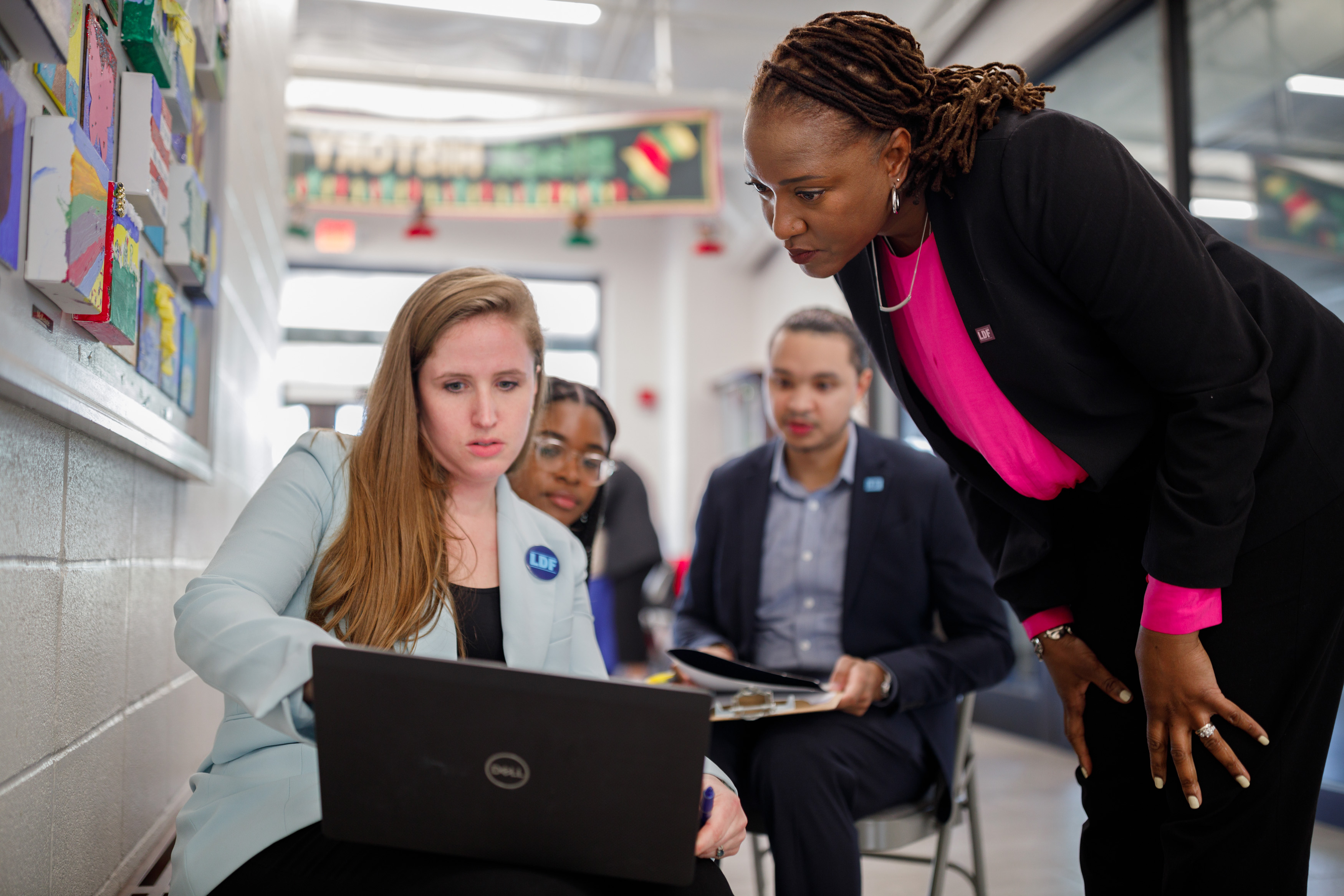 LDF volunteers at a poll site, viewing a laptop screen together