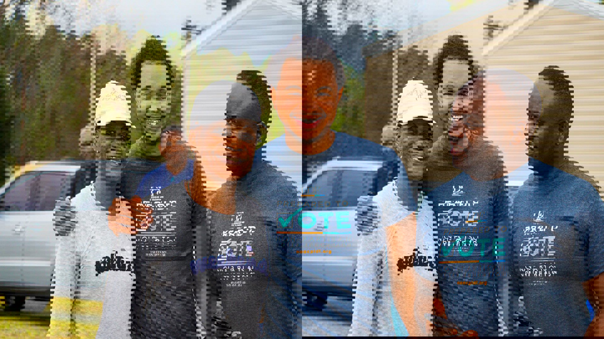 Picture of three Black people smiling with voting shirts.